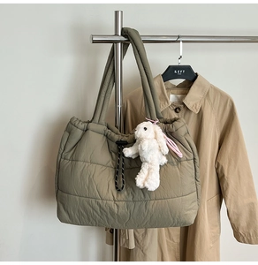 Detail of olive green quilted puffer tote bag with black drawstring and bunny charm