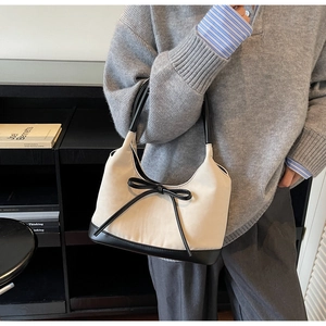Detail showing the chic bow tie and black contrast strap on the cream underarm bag