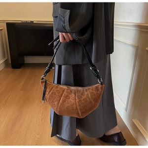 Detail of leopard print faux suede crescent bag with knotted black leather handle