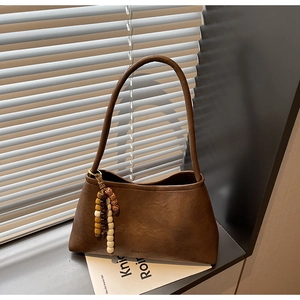Close-up of dark brown leather handbag featuring a colorful wooden bead tassel and logo
