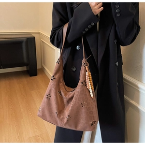 Détail du motif floral ajouré sur le sac cabas en daim marron avec pompon de style ethnique