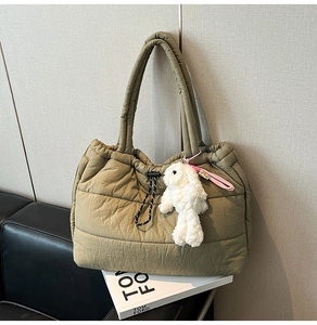 Detail of olive green quilted tote bag with drawstring feature and plush bunny charm