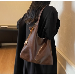 Detail of dark brown tote bag featuring white contrast stitching and a wooden bead tassel