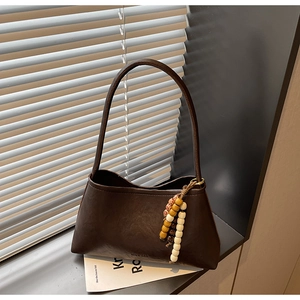 Close-up of retro brown shoulder bag with a unique wooden bead charm detail