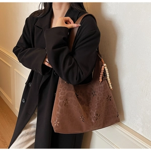 Détail d'un sac cabas en daim marron avec fleurs découpées au laser et imprimé léopard