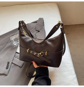 Vista dettagliata della borsa sottobraccio in pelle marrone scuro con fibbia dorata e zip