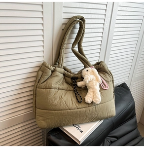 Detail of olive green quilted puffer tote bag with cute white bunny charm accessory