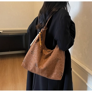 Détail de motifs floraux ajourés et imprimé léopard sur un sac fourre-tout brun