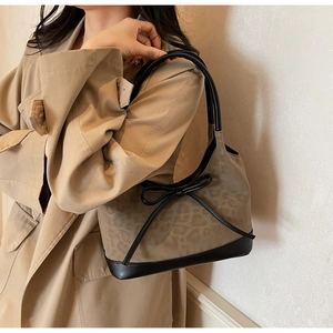 Detail of leopard print tote bag with black bow and leather accents worn with a trench coat
