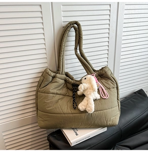 Detailed close-up of olive green quilted tote bag with cute plush rabbit charm