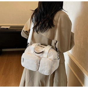 Detail of white nylon crossbody bag with multiple zip pockets shown on model