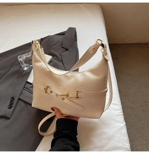 Dettaglio della borsa hobo crema con fibbie dorate su uno sfondo bianco pulito