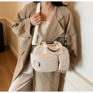 Detailed view of beige canvas tote bag with functional exterior pockets and wide shoulder strap