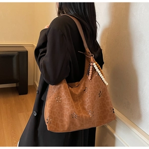 Détail du sac hobo marron avec découpes fleuries et imprimé léopard avec gland perlé