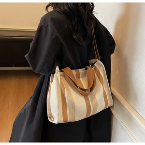 Vertical striped canvas tote bag shown worn on shoulder in a cozy home setting