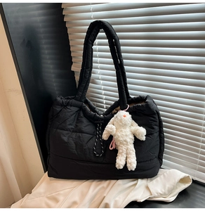 Detail of black quilted tote bag with drawstring closure and cute white bunny charm