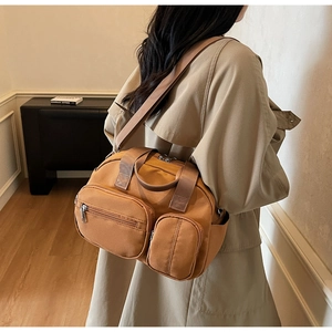 Detail of earth-tone nylon crossbody bag showing multiple functional zipper pockets