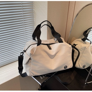 Detailed macro view of white nylon travel bag with black straps and logo on wood desk