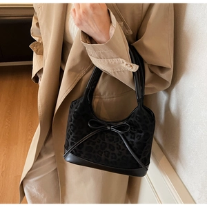 Detail of leopard print handbag with leather bow, shown styled with a trench coat