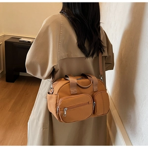 Detailed view of earth-tone nylon crossbody bag with dual zippered front pockets and strap