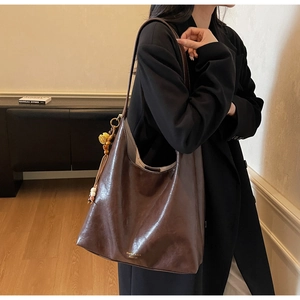 Detail of vintage brown leather tote bag showing smooth texture and fringe tassel charm