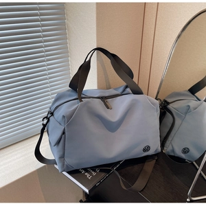 Detail of blue waterproof nylon travel bag with logo and natural light shadows
