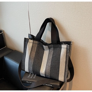 Detail of multi-color striped canvas tote bag with black strap and durable weave texture