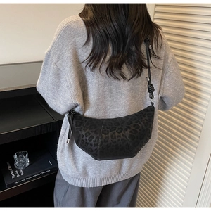 Detail of black leopard print crossbody croissant bag on a textured shoulder strap