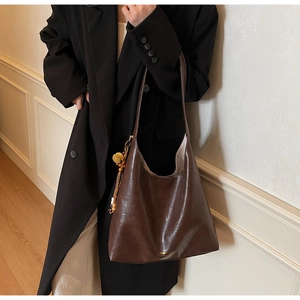 Close-up of deep coffee oil-wax leather tote with a sunflower charm and gold lettering