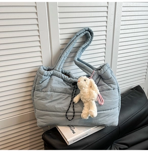 Detail view of blue quilted puffer tote bag with drawstring and white bunny charm