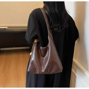 Detail of soft brown leather Hobo bag featuring gold logo and spacious round design