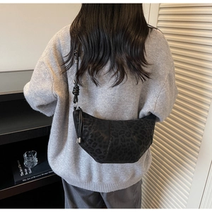Detail of black leopard print crescent bag with knot strap shown on a model's back
