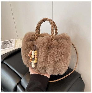 Detail der Plüschhandtasche aus braunem Kunstpelz mit Ledergriffen und Perlenanhänger