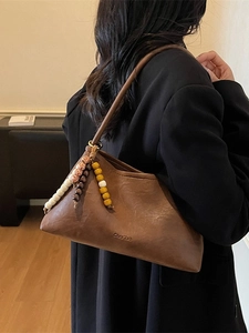 Vintage brown geometric shoulder bag with colorful beaded tassels shown on a model