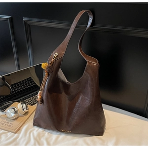 Detailed close-up of deep brown tote bag with contrast stitching and decorative charms