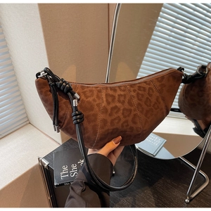 Detail view of leopard print crescent bag with leather knot straps and silver metal hardware