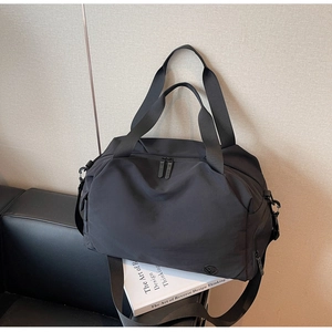 Detail of black travel bag showing durable nylon texture, handles, and branding logo