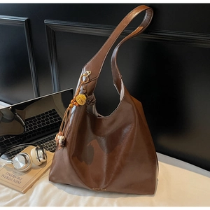 Detail of soft brown leather tote with ethnic tassels and brand logo on a desk