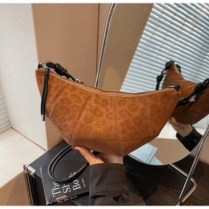 Detail view of caramel brown leopard print croissant bag with woven shoulder strap