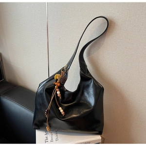 Detailed macro view of large black shiny leather tote with retro tassel and wooden bead detail