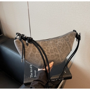 Detail shot of leopard print crescent bag in suede leather with knot strap and metal accents