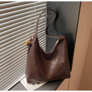 Detail of vintage brown oil-wax leather hobo tote bag with stylish yellow tassel accent