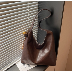 Detail of a large vintage brown tote bag with leather texture and pompom fringe