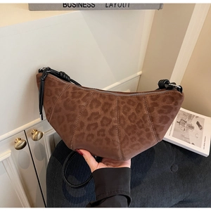 Detail of a brown leopard print crescent bag featuring a knot handle and metal zipper