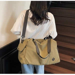 Olive green travel bag with side flap pocket and shoulder strap shown on a model