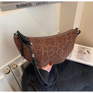 Detail of a brown leopard print suede croissant bag with a black knotted strap handle