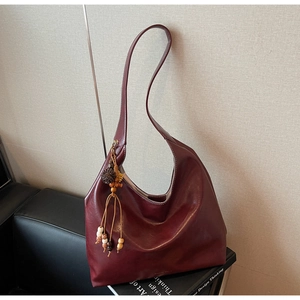 Detail of vintage burgundy hobo bag featuring wood bead tassel and soft matte texture