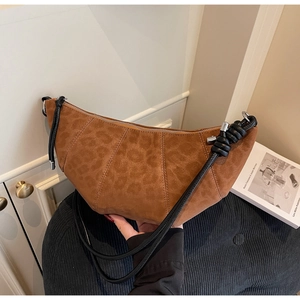 Close-up of brown leopard print croissant bag with braided strap and silver zipper detail
