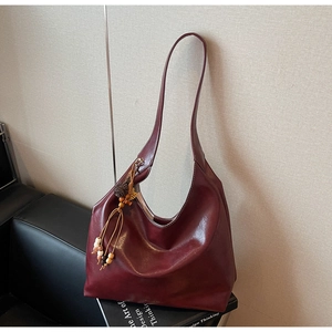 Deep red tote bag detail featuring a vintage bead tassel and smooth textured leather finish