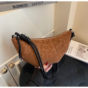 Detail of leopard print croissant bag showing brown suede texture and knotted straps